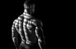 © Olya - Muscular man showing defined back muscles with dramatic striped shadows in black and white against a dark background conveying strength and focus