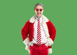 © Studio Romantic - Cheerful bearded man Santa Claus wearing stylish red sunglasses and costume opens mouth from excitement, happy to hear nice, isolated over green background. Winter holidays concept