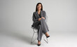 © opolja - Portrait of a cheerful young businesswoman sitting in a chair against white background.