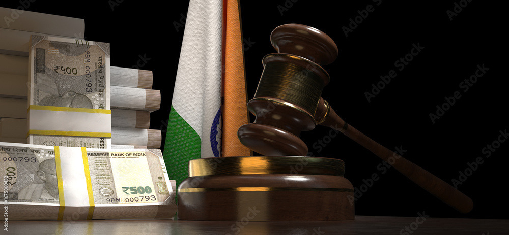 A wooden gavel and a stack of Indian rupee banknotes rest on a table in front of the Indian national flag.