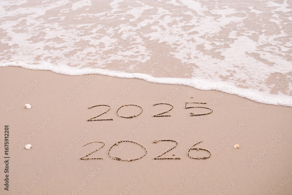 Handwritten inscription 2025 and 2026 on the beach in the sunset time ...