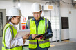 © JD Studio - Construction Workers Collaborating on Project Plans in Safety Gear at Industrial Site