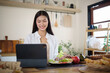 © matinee - Beautiful Asian woman enjoying morning routine, working on digital tablet with fresh meal on wooden table.