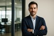 © Pixels Hunter - Confident businessman in suit standing with arms crossed in modern office interior near glass wall, blank background on right side for copyspace. Ai generative
