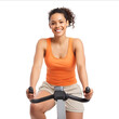 © axmilasky - A beautiful woman smiling riding an exercise bike wearing an orange tank top and beige shorts isolated on a white background highresolution photography