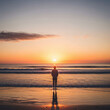 © Clark Still - Silhouette of person contemplating sunrise ocean beach peaceful inspirational background for meditation wellness website