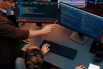 Top view of IT developers discussing with point to intelligent website development coder system running data online two screens information technology at neon light room at modern office. Infobahn.