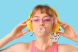 © Pixel-Shot - Beautiful young woman in headphones with chewing gum on blue background, closeup