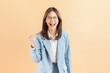 © sitthiphong - Excited Asian businesswoman raised hands celebrating success isolated against a beige background.