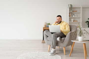 Poster - handsome man using laptop in grey armchair at home