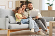 © Pixel-Shot - Happy parents with their daughter watching cartoons on laptop at home