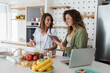 © Dorde - Two Happy Women Cooking in a Bright Modern Kitchen Using Fresh Ingredients and a Tablet