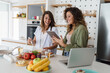 © Dorde - Young Happy Women Friends Cooking Together in a Bright Modern Kitchen with Fresh Ingredients