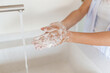 © Dorde - Young Woman Washing Hands with Soap in Bright Modern Kitchen Sink