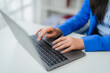 © Parichat - Businesswoman typing on laptop keyboard in bright office