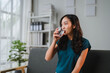© Parichat - Young asian woman drinking fresh water from glass in office