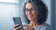 © Yessy - Happy mature woman with curly gray hair using a modern smartphone.