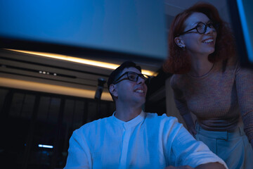Two software developers collaborating at night, focusing on code review and debugging process on a computer screen, representing teamwork, innovation, and modern software development workflow.