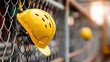 © Ehsan - Safety helmet hanging on chain-link fence
