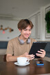 © Ranta Images - Young Thai student man in coffee shop wearing headphones using digital tablet computer
