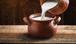 © Annalise - filling ceramic pot with fresh milk on rustic wooden table indoors