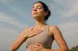 © luengo_ua - Calm woman practicing breathing exercise outdoors with hands on chest and stomach.