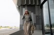 © Ivan Traimak - Senior woman leaving modern building while talking on smartphone in urban setting during daylight