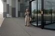 © Ivan Traimak - Older woman using smartphone while waiting outside modern building in urban area
