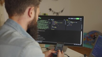 Software developer working from home using smartphone and computer