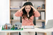 © ArLawKa - A stressed Asian female real estate businesswoman is working at her desk in an office.