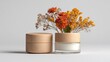 © Breken - Two light beige wooden-lidded jars, one slightly angled in front of the other, with a small bouquet of dried orange and yellow flowers in the center.  White cream in a glass jar