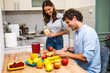 © djoronimo - Adult couple is preparing smoothie in their kitchen. They have various fruits ready to be mixed in electric juicer.