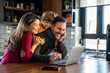 © NDABCREATIVITY - Happy young family with kids in kitchen have fun using modern laptop together, enjoying weekend
