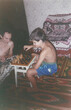 © Masson - Father and ten-year-old son playing chess in home room during summer vacation, captured in film photography style from early 1990s in Ukraine