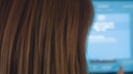 Close up rear view of service woman operating blur touch screen machine, finger presses buttons on interface, blue glow from display, indoor self service payment terminal, modern technology workflow
