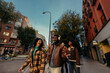 © bernardbodo - Group of happy young friends walking down the street listening to music and laughing