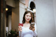 © Natthawadee - A happy young Asian woman smiles while holding shopping bags and a credit card, representing fashion, lifestyle, wealth, retail, and cheerful consumerism.
