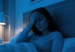 © AHMMAD - A woman is suffering from a headache and insomnia in her bedroom at night