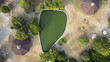 Aerial view of a tranquil pond reflecting the sky, fringed by verdant trees and quaint octagonal structures, offering a peaceful oasis from above, Lagos, Lagos, Nigeria.