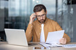 © Liubomir - Businessman feeling stressed reading documents at workplace