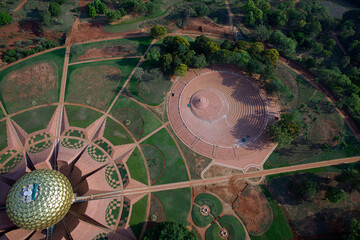 Aerial view of the Matrimandir complex with its golden orb reflecting the sun, surrounded by meticulously designed gardens and pathways, Bommayapalayam, Tamil Nadu, India.