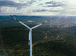© AmazingAerialAgency - Aerial view of towering wind turbines stand as sentinels amidst the undulating green hills, their blades catching the sun's rays, Hosur, Karnataka, India.