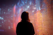 © Percy Lou - Defocused shot of a female standing against illuminated LED digital display screen in the dark. Futuristic concept. Connecting to the future. Interaction between human and technology. Technology and i