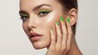 © Maria - Woman with neon green eyeliner and nails against soft neutral monochrome backdrop