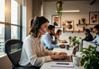 © Filip - Female call center agent with a headset working on a laptop in a busy modern office