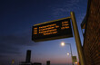  Illuminated digital bus stop sign displaying arrival times at dusk
