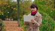 © Victoriia - Portrait of business lady using tablet computer in autumn park. Young attractive woman looking at tablet screen outdoors. Elegant business woman using online with digital device outside. Fashion, girl