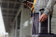 © Wavebreak Media - African american man waiting on station platform using smartphone and pulling suitcase