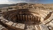 © Garan - High-angle view of a circular, ancient stone structure with surrounding ruins and a dry landscape.