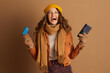 © Alliance - A joyfully laughing woman in autumn fashion holds a credit card and smartphone, embodying the excitement and convenience of digital shopping and financial transactions.